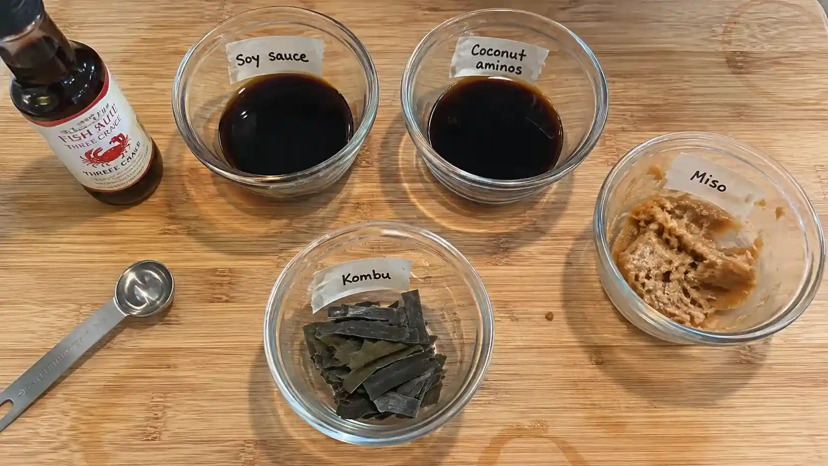 fish sauce substitute ingredients in small bowls on a wooden kitchen counter