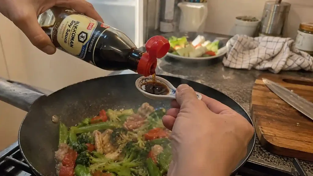 pouring soy sauce as a 1:1 fish sauce substitute into a stir-fry